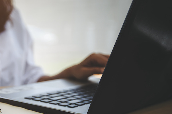 A person seated at a desk types on a computer.